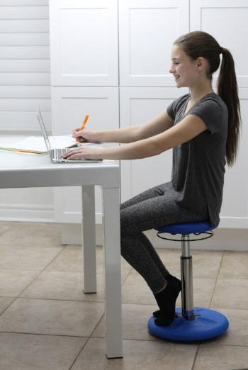 Girl using Kore Kids Height-Adjustable Wobble Chair at desk from Active Goods Canada