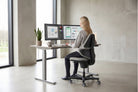 Woman working at a standing-height desk on a Clay CoreChair Elite