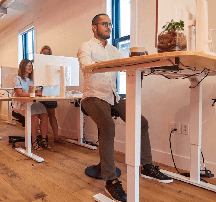 CorePerch Active Stool perching at standing office desk by Active Goods Canada